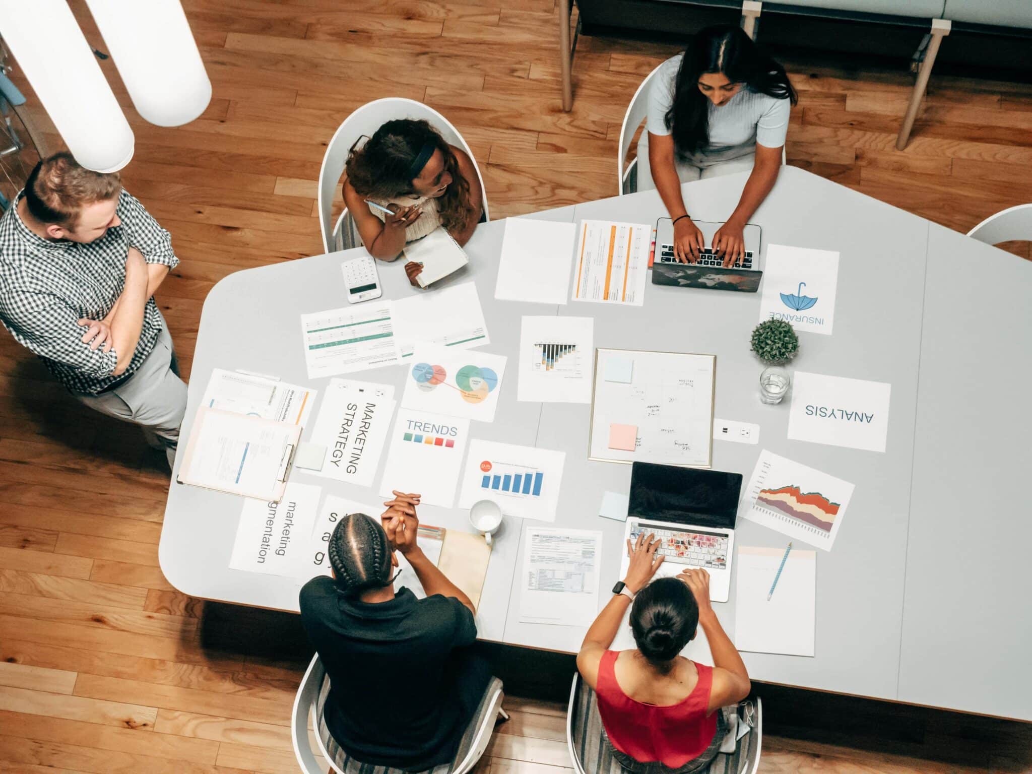 Marketing team collaborating around a table with strategy documents and data